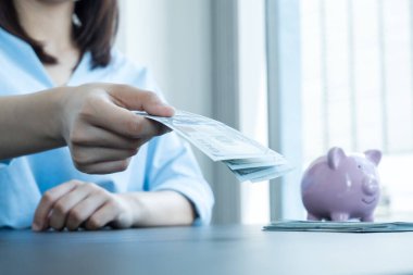 Para biriktirmek, işleri büyütmek ve emeklilik için biriktirmek için kadınların elleri dolar tutuyor ve domuz kumbaraları koyuyor..