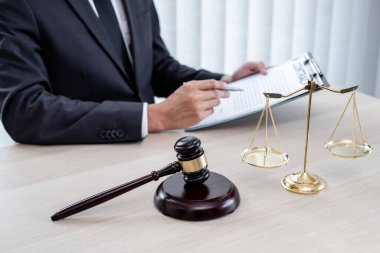 Yargıç tokmağı, profesyonel erkek avukatlar bir hukuk bürosunda çalışıyor. Teraziler, adalet terazileri, yargıç tokmağı ve dava belgeleri var. Hukuk ve adalet kavramları.