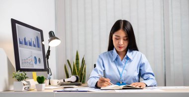 Asyalı kadınlar masalarında oturup yatırımlarıyla ilgili sonuçları gösteren mali grafikleri hesaplıyor ve başarılı bir iş büyüme süreci planlıyorlar..