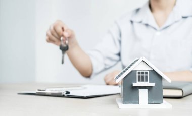 Ev tasarımları ve kira belgeleri ile anahtar taşıyan emlak yatırımcıları, ev satın alma sözleşmeleri, ev sigortası ve müşteriler için satın alma onayı.