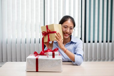 Asyalı kadın bir hediye kutusu tutuyor. Bayramlarda, Noel 'de, doğum günlerinde ya da Sevgililer Günü konseptinde sürpriz yapmaktan mutluluk duyuyor..