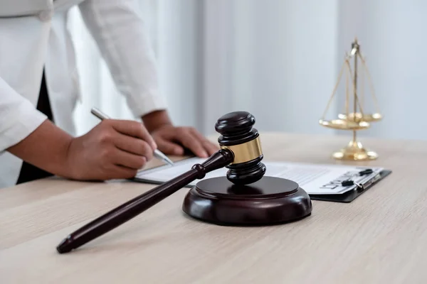 Profesyonel kadın avukatlar bir hukuk bürosunda çalışıyor. Teraziler, adalet terazileri, yargıç tokmağı ve dava belgeleri var. Hukuk ve adalet kavramları.