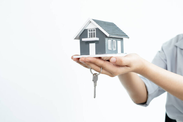 The hand of the real estate agent holding the house model and the keys Loan and home concept.