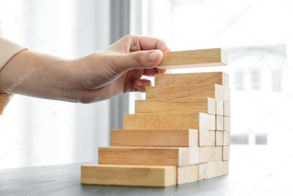 Hands of businesswomen playing wooden block game. Concept Risk of management and strategy plans for business growth and success.