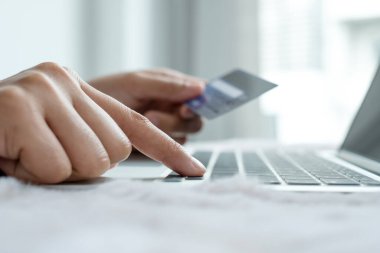 İş kadınının elinde bir kredi kartı var ve ofisteki online alışveriş ve internet ödemeleri için bir dizüstü bilgisayar kullanıyor..