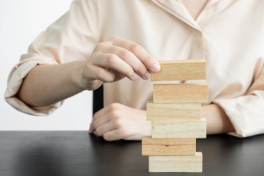 Ahşap blok oyunu oynayan iş kadınlarının elleri. Ticari büyüme ve başarı için yönetim riski ve strateji planlarını kabul et.