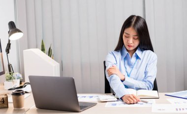 Asyalı kadın muhasebeci, bir sandalyede çalışmaktan, dinlenmek için kollarını açmaktan ve ofiste sıkı çalışmaktan yoruldu..