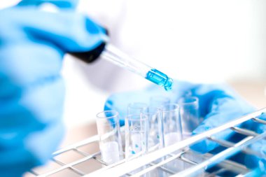 Tıp bilimcileri bir kimya laboratuvarında virüsü analiz etmek için test tüpüne bir örnek pipet yerleştirdiler. Bilimsel araştırma kavramları.