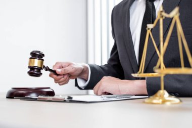 Yargıç tokmağı, profesyonel erkek avukatlar bir hukuk bürosunda çalışıyor. Teraziler, adalet terazileri, yargıç tokmağı ve dava belgeleri var. Hukuk ve adalet kavramları.