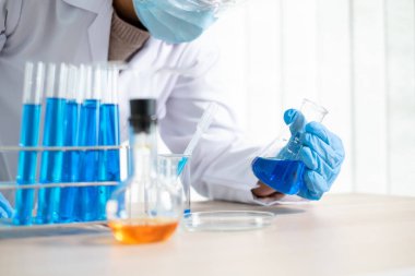 Tıp bilimcileri bir kimya laboratuvarında virüsü analiz etmek için deney şişesine yerleştirilmiş bir örnek bıraktılar. Bilimsel araştırma kavramları.