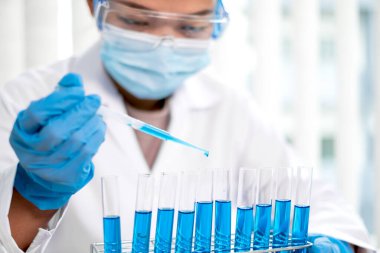 Tıp bilimcileri bir kimya laboratuvarında virüsü analiz etmek için test tüpüne bir örnek pipet yerleştirdiler. Bilimsel araştırma kavramları.