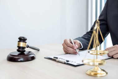 Profesyonel erkek avukatlar bir hukuk bürosunda çalışır. Teraziler, adalet terazileri, yargıç tokmağı ve dava belgeleri vardır. Hukuk ve adalet kavramları.