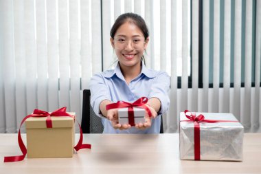 Asyalı kadın bir hediye kutusu tutuyor. Bayramlarda, Noel 'de, doğum günlerinde ya da Sevgililer Günü konseptinde sürpriz yapmaktan mutluluk duyuyor..