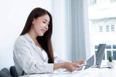 Asyalı kadın muhasebeci masalarında oturup yatırımlarıyla ilgili sonuçları gösteren mali grafikleri hesaplar ve başarılı bir iş büyüme süreci planlar..