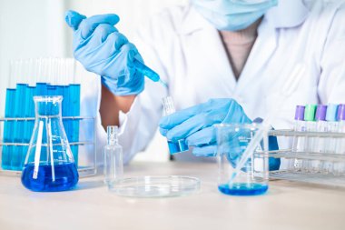 Tıp bilimcileri bir kimya laboratuvarında virüsü analiz etmek için deney şişesine yerleştirilmiş bir örnek bıraktılar. Bilimsel araştırma kavramları.