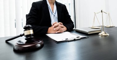 Profesyonel kadın avukatlar bir hukuk bürosunda çalışıyor. Teraziler, adalet terazileri, yargıç tokmağı ve dava belgeleri var. Hukuk ve adalet kavramları.