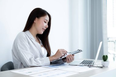 Asyalı kadın muhasebeci masalarında oturup yatırımlarıyla ilgili sonuçları gösteren mali grafikleri hesaplar ve başarılı bir iş büyüme süreci planlar..