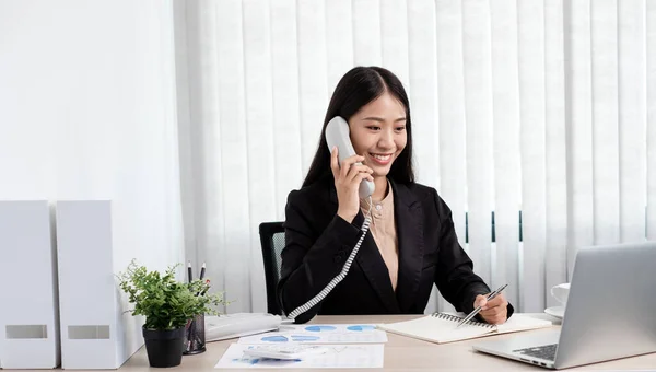 オフィスで働いている間 アジアのビジネスマンは電話で話し 明るく幸せな笑顔でラップトップで働いています — ストック写真