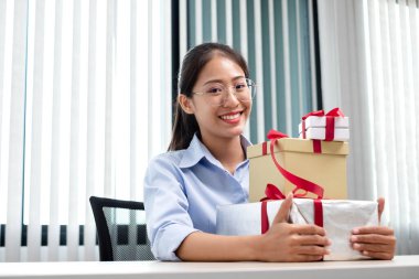 Asyalı kadın bir hediye kutusu tutuyor. Bayramlarda, Noel 'de, doğum günlerinde ya da Sevgililer Günü konseptinde sürpriz yapmaktan mutluluk duyuyor..