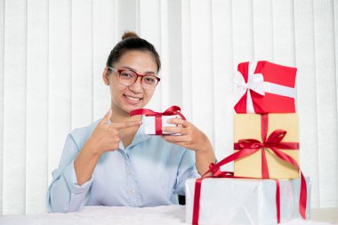 Asyalı kadın bir hediye kutusu tutuyor. Bayramlarda, Noel 'de, doğum günlerinde ya da Sevgililer Günü konseptinde sürpriz yapmaktan mutluluk duyuyor..