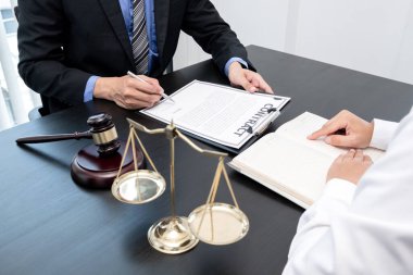 Bir erkek avukat ya da bir yargıç müvekkillerine yargı adaleti ve kovuşturma hakkında ölçekli danışmanlık yapıyor..