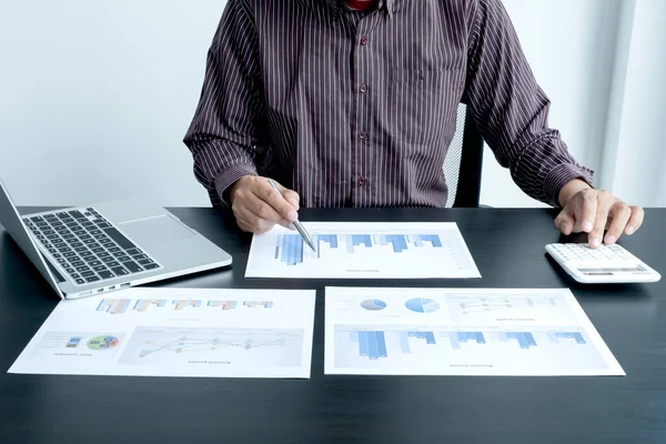 The hands of a male businessman are analyzing and calculating the annual income and expenses in a financial graph that shows results To summarize balances overall in office.