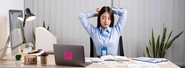 アジアの女性会計士は椅子で仕事をするのに疲れ オフィスで一生懸命仕事をしながらリラックスしてリラックスしています — ストック写真