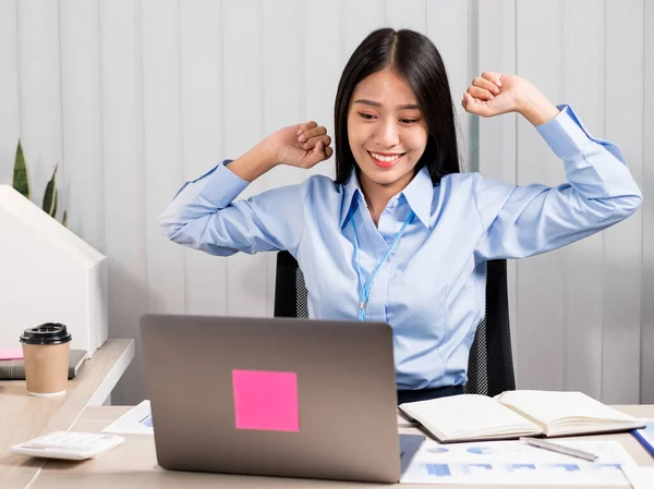 Asian female accountant is tired from working in a chair, stretching to relax and relax while working hard at the office.