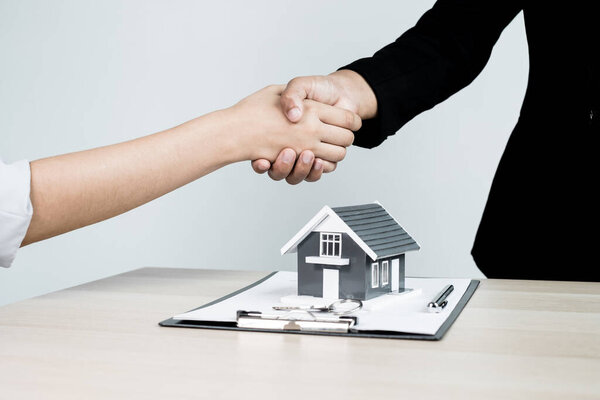 Businessmen and brokers real estate agents shake hands after completing negotiations to buy houses insurance and sign contracts. Home insurance concept.