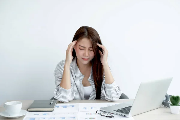 Working Asian women feel stressed, tired from work, migraine headaches from hard work while working at the office.