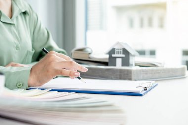 Tasarımcı evin içini planlıyor. Masasında örnek malzemeler olan yeni ev için mükemmel renkleri çiziyor ve seçiyor. Gayrimenkul tasarım işi fikirleri.