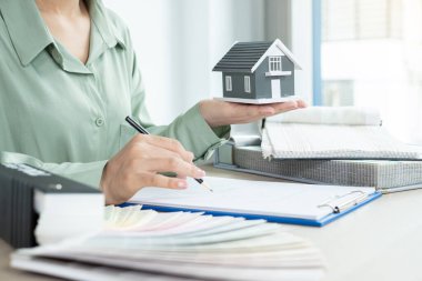 Tasarımcı evin içini planlıyor. Masasında örnek malzemeler olan yeni ev için mükemmel renkleri çiziyor ve seçiyor. Gayrimenkul tasarım işi fikirleri.