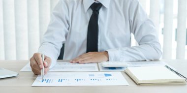 İş adamı masalarında oturur ve başarılı iş büyümesi sürecini planlayan yatırımlarının sonuçlarını gösteren mali grafikleri hesaplar.