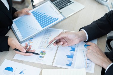 İki iş lideri çizelgeler, finansal grafikler hakkında konuşuyor. Sonuçları gösteren planlama stratejilerini analiz ediyor ve hesaplıyor. Ticari başarı oluşturma süreçlerini de..