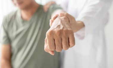 Kadın fizyoterapistler, erkek hastalara omuz yaralanmalarında fiziksel yardım sağlıyor rehabilitasyon merkezinde kas tedavisi için omuzlarına masaj yapıyorlar. Fizyoterapi kavramları.