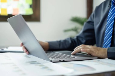 İş adamı masalarında oturur ve başarılı iş büyümesi sürecini planlayan yatırımlarının sonuçlarını gösteren mali grafikleri hesaplar.