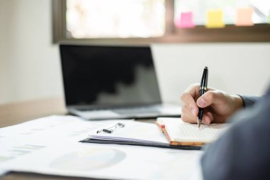 İş adamı masalarında oturur ve başarılı iş büyümesi sürecini planlayan yatırımlarının sonuçlarını gösteren mali grafikleri hesaplar.