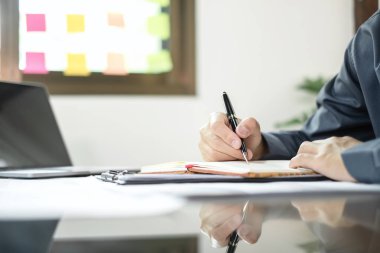 İş adamı masalarında oturur ve başarılı iş büyümesi sürecini planlayan yatırımlarının sonuçlarını gösteren mali grafikleri hesaplar.