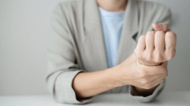 Bileğinde ağrı, avucunda uyuşukluk ve ağrı olan bir kadın elinin sinir uçlarında ağrı ve karıncalanma vardır. Bu ofiste uzun süre oturup çalışmanın bir yan etkisidir..