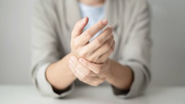 Bileğinde ağrı, avucunda uyuşukluk ve ağrı olan bir kadın elinin sinir uçlarında ağrı ve karıncalanma vardır. Bu ofiste uzun süre oturup çalışmanın bir yan etkisidir..