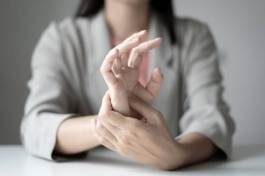 Bileğinde ağrı, avucunda uyuşukluk ve ağrı olan bir kadın elinin sinir uçlarında ağrı ve karıncalanma vardır. Bu ofiste uzun süre oturup çalışmanın bir yan etkisidir..