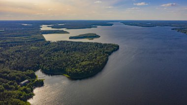 gün batımı ve kümülüs bulutları ile gölün yakınındaki ormanda ev