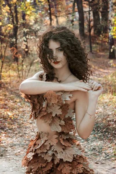 秋の朝 秋の女の子 オークの葉をしたドレス姿で森の中を歩く少女 — ストック写真