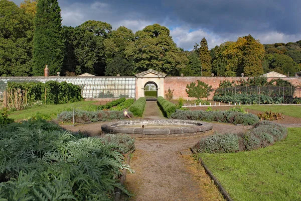 Ommuurde moestuin met een pad en een cirkelvormige fontein. — Stockfoto