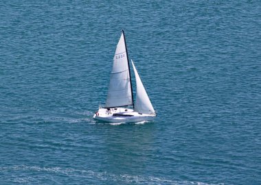 Kuzey Adası 'nda Maunganui Dağı 'nı çevreleyen turkuaz denizde bir yat yelken, Yeni Zelanda.