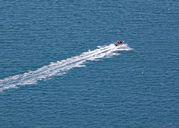 A motor boat speeds across the turquoise sea that surrounds Mount Maunganui in North Island, New Zealand.