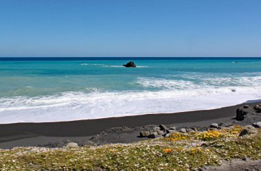Dalgalar ve köpük Cape Palliser, North Island, Yeni Zelanda 'da ıssız plaja kadar yıkayın
