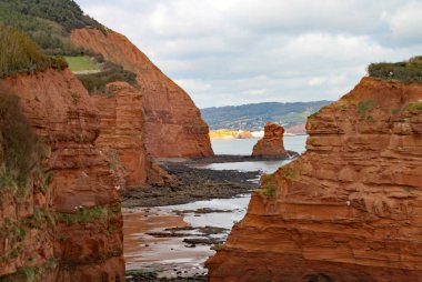 Sidmouth, Devon yakınlarındaki Ladram Körfezi'nde bir kumtaşı deniz yığını. Güney batı kıyı yolunun bir parçası. Sidmouth arka planda görünür.