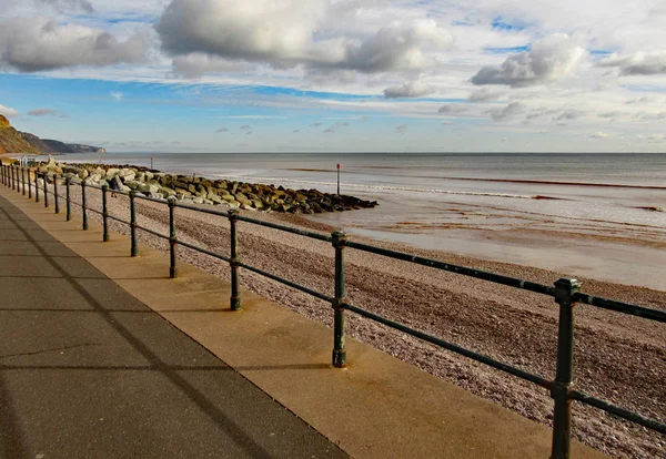 Металлические перила на Sidmouth Esplanade, чтобы остановить людей, падающих на галечный пляж около 3 метров ниже . — стоковое фото