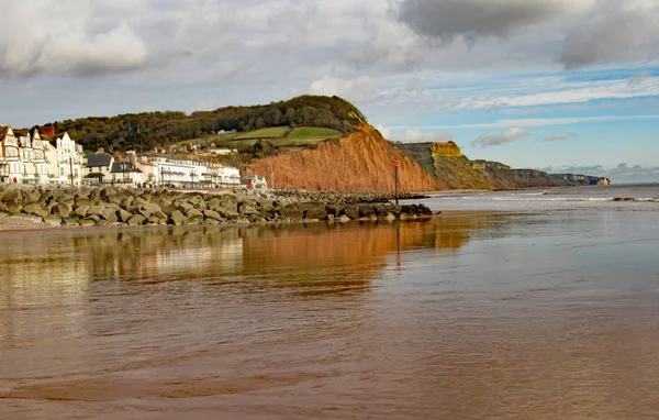 View of the eastern end of Sidmouth Esplanade and sandstone cliff. This cliff has regular rockfalls which reduce the lengths of the gardens on top. Stock Image